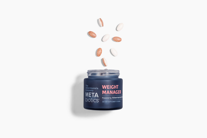 Navy jar of METAbiotics Weight Manager supplement with pink and white tablets floating above