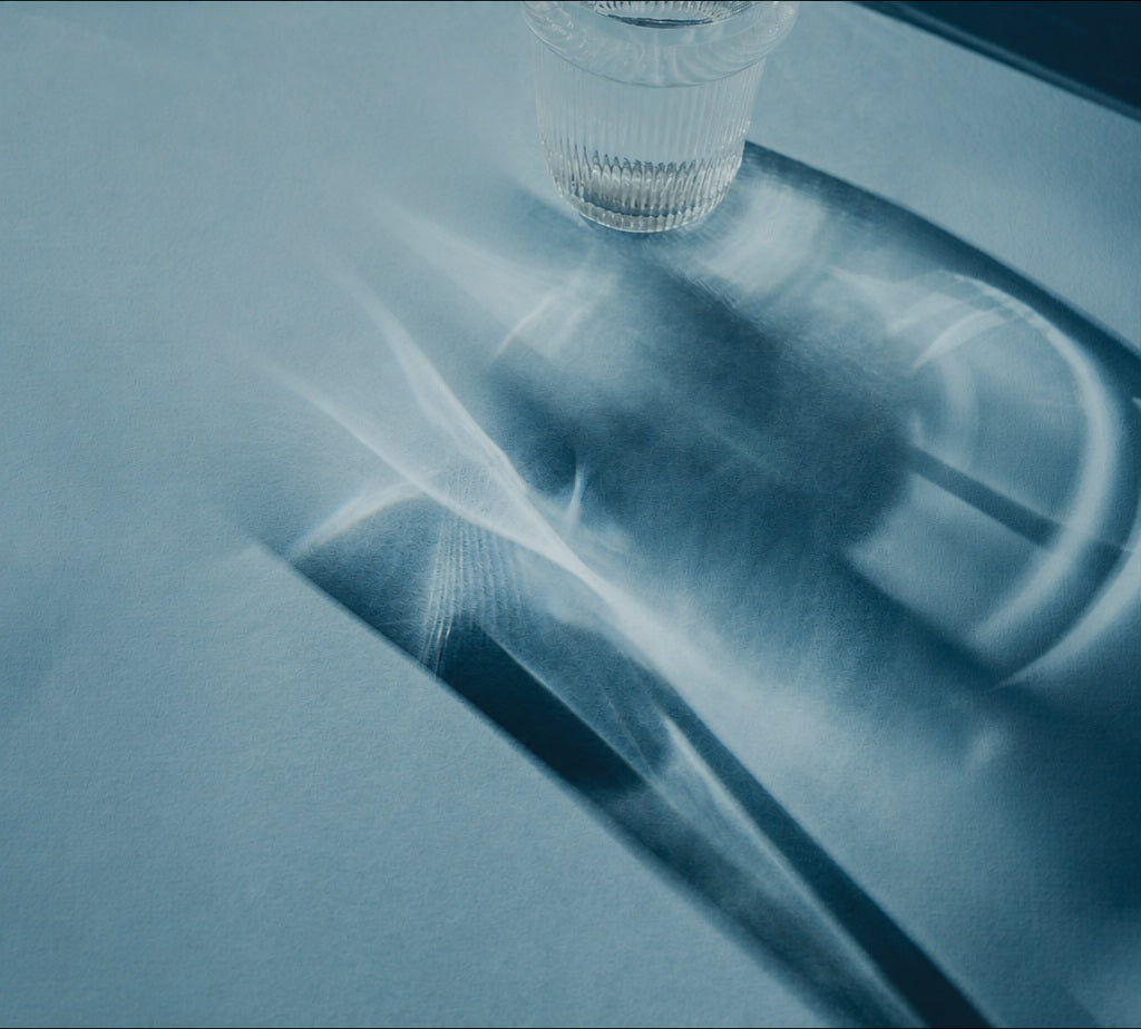 Blue textured surface with a glass of water and soft shadows